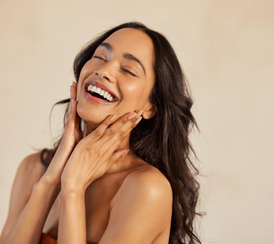 Happy, beautiful woman touching her face